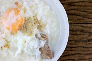 Ev yapımı Tayland pilavı çorbası tavuk, domuz eti ve haşlanmış yumurta ya da taşra ahşap arka planda beyaz darbeyle onsen yumurtası. Tayland usulü yemek. Üst görünüm.