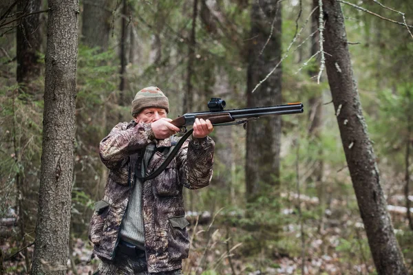 Der männliche Jäger schießt mit einem Gewehr. bewölkt, Herbst. — Stockfoto