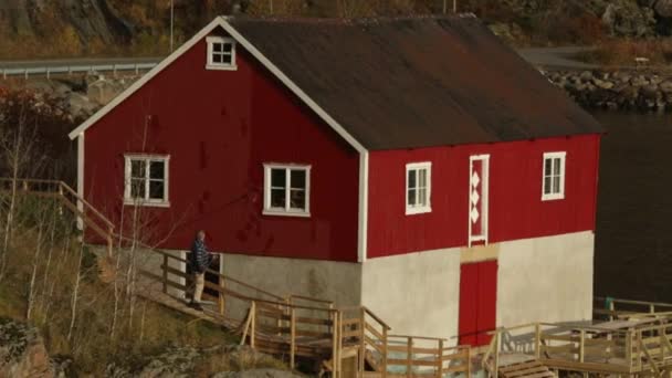 Ο άνθρωπος χρωματίζει ένα σπίτι με κόκκινο χρώμα — Αρχείο Βίντεο