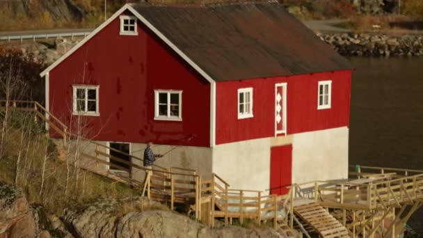 Человек красит дом в красный цвет — стоковое видео