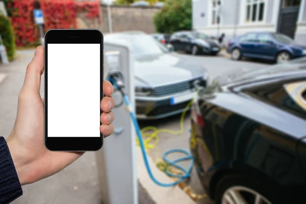 Mão com telefone em um contexto de carros elétricos — Fotografia de Stock