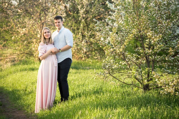 Jovem casal grávida em um parque de primavera — Fotografia de Stock