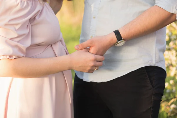 Jovem casal grávida em um parque de primavera — Fotografia de Stock