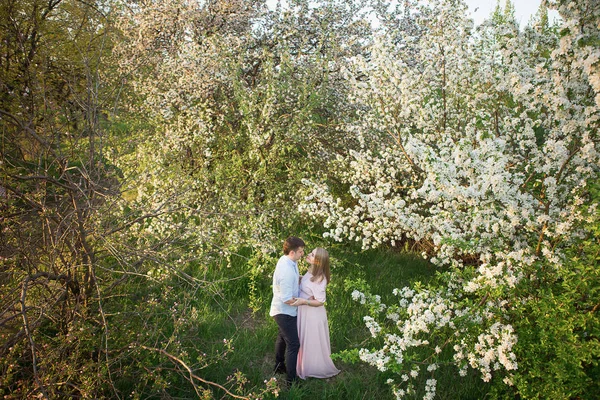 Jovem casal grávida em um parque de primavera — Fotografia de Stock