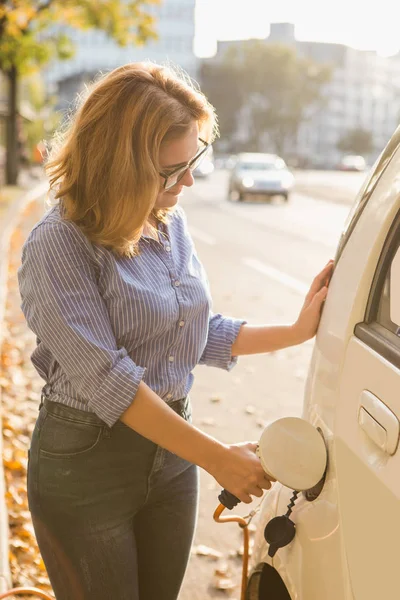 Giovane donna sta caricando un'auto elettrica . — Foto Stock