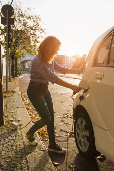 Jovem está carregando um carro elétrico . — Fotografia de Stock