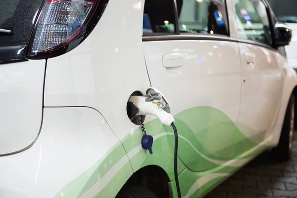 Coche eléctrico cargado en una estación de carga en un aparcamiento cubierto —  Fotos de Stock