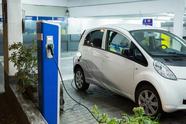 Samochód elektryczny na stację ładującą w kryty parking — Zdjęcie stockowe