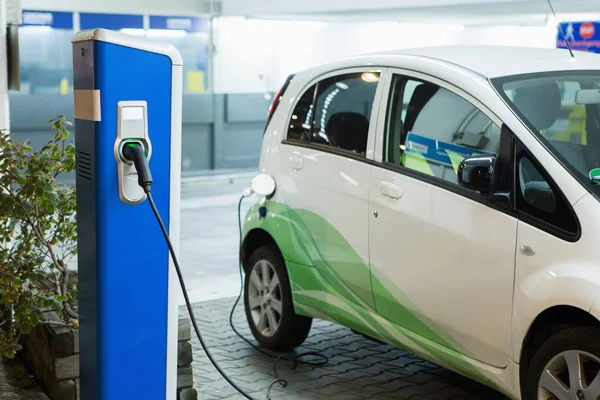 Coche eléctrico cargado en una estación de carga en un aparcamiento cubierto —  Fotos de Stock