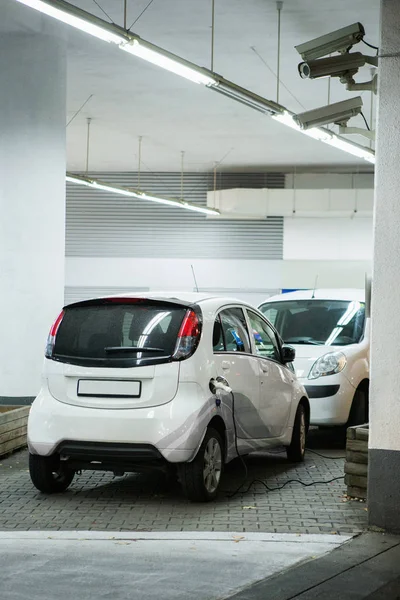 Ηλεκτρικό αυτοκίνητο χρεώνεται σε ένα σταθμό φόρτισης σε ένα εσωτερικό χώρο στάθμευσης — Φωτογραφία Αρχείου