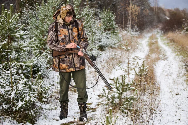 Hunter with a backpack and a hunting gun in the winter forest. — Stock Photo, Image