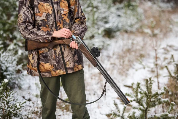 Hunter con una mochila y un arma de caza en el bosque de invierno . — Foto de Stock