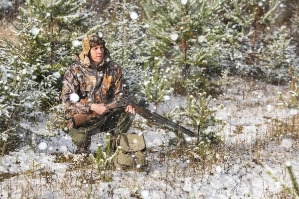 Hunter s batohem a loveckých zbraní v zimním lese. — Stock fotografie