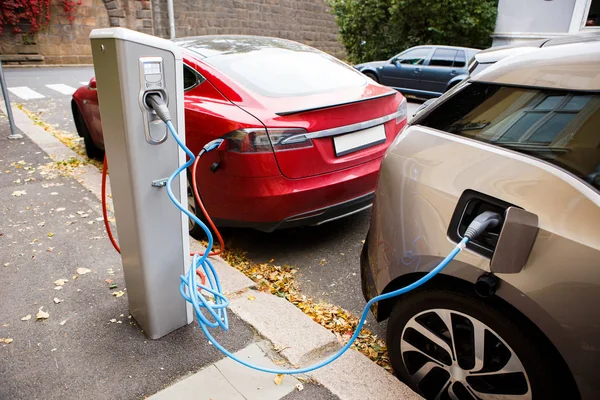 Stock photo of an electric vehicle plugged into a charging station on a city street