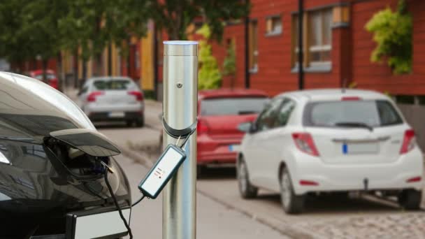 L'auto elettrica è a pagamento nel parcheggio vicino alla casa. L'indicatore di processo di ricarica lampeggia. Zoom della fotocamera si muove in avanti . — Video Stock