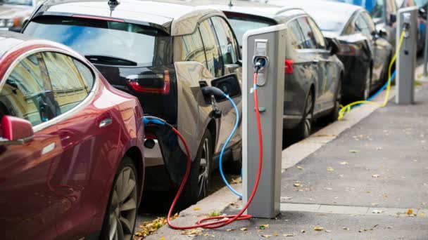 Многие электромобили заряжаются зарядными станциями на парковке . — стоковое видео
