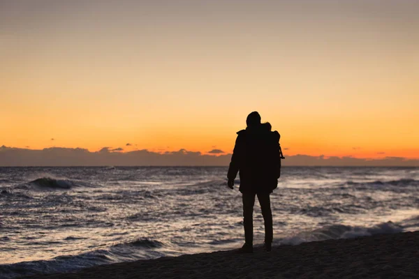 Man reiziger met een rugzak staat op het strand — Stockfoto