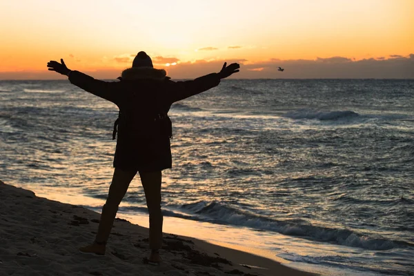 Hombre viajero con una mochila está de pie en la playa — Foto de Stock