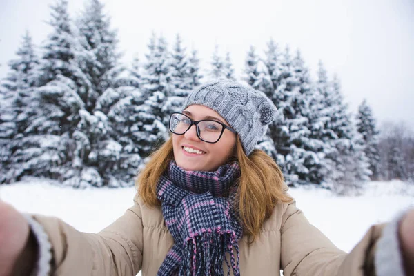 Giovane donna prende selfie su uno sfondo di foresta invernale innevata. — Foto Stock