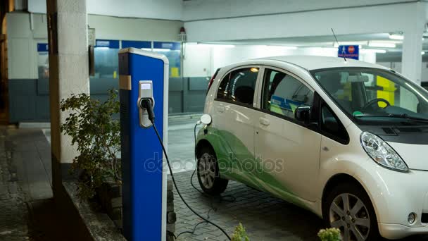 屋内駐車場で電気自動車の充電はカーシェア リング 駅のインジケーターは緑を点滅します カメラのズームをオブジェクトに移動します — ストック動画