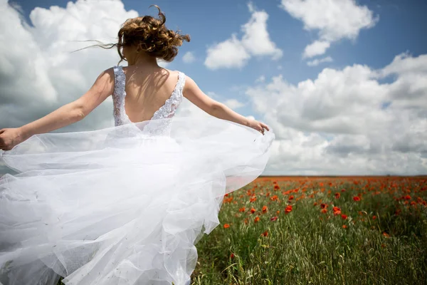 Bruden som körs på ett fält av blommande vallmor — Stockfoto