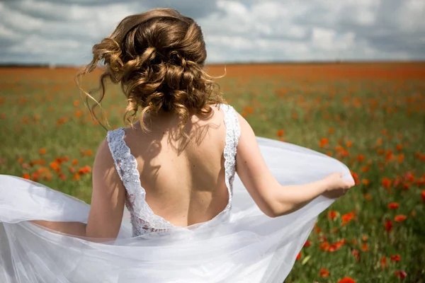 Noiva correndo em um campo de papoilas florescendo — Fotografia de Stock