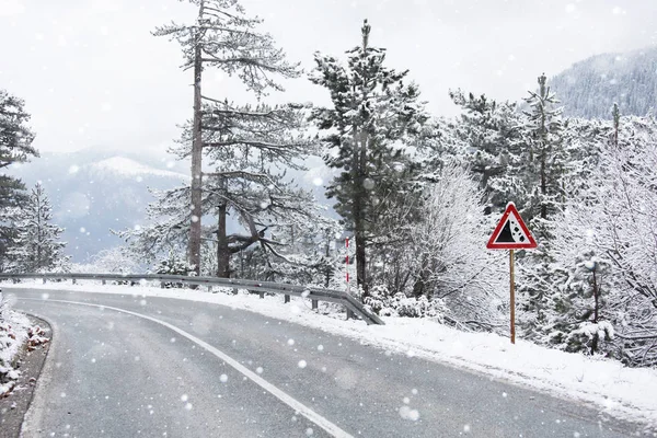 Горная зимняя дорога с предупреждающим знаком — стоковое фото