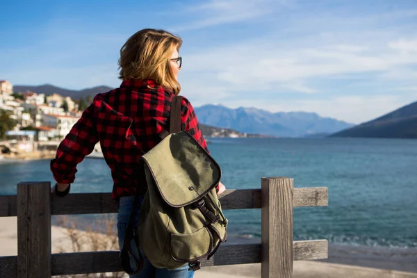 Mulher em uma camisa com uma mochila está de pé em um cais de madeira — Fotografia de Stock