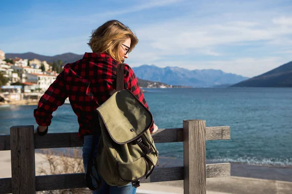 Mulher em uma camisa com uma mochila está de pé em um cais de madeira — Fotografia de Stock