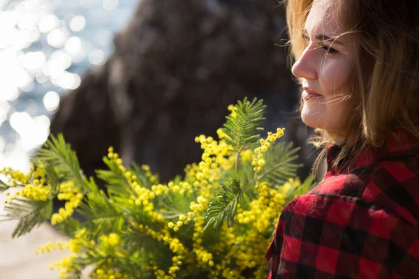 Portrait d'une femme tenant un bouquet de fleurs de mimosa . — Photo