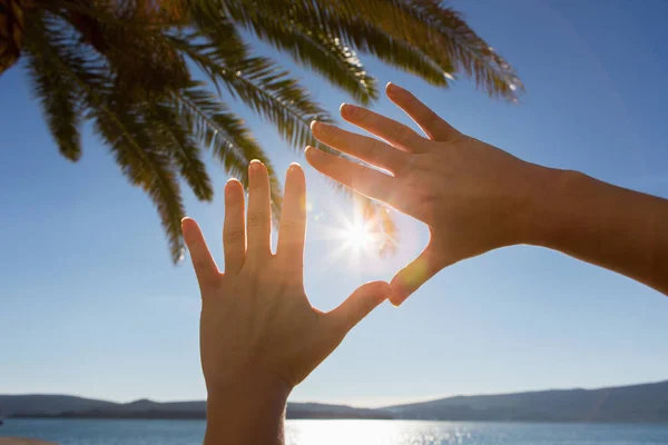 A woman shields the sun with her hands. — Stock Photo, Image