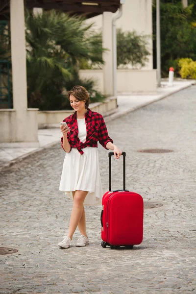 Молодая женщина путешественница с чемоданом и телефоном — стоковое фото
