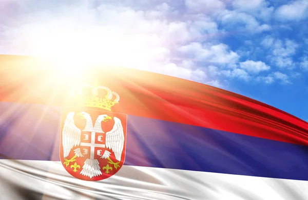 flag of Serbia against the blue sky with sun rays