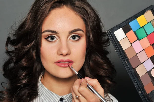 Makeup artist paints a very pretty brunette — Stock Photo, Image