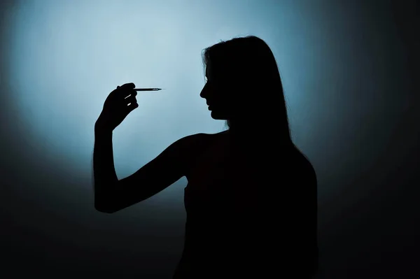 Syringe and girl silhouette on a blue background — Stock Photo, Image