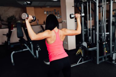 Sportif kız dumbbells ile egzersiz yaparak.