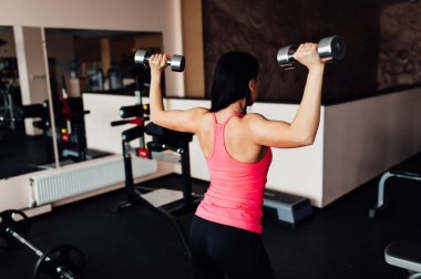 Sportif kız dumbbells ile egzersiz yaparak.