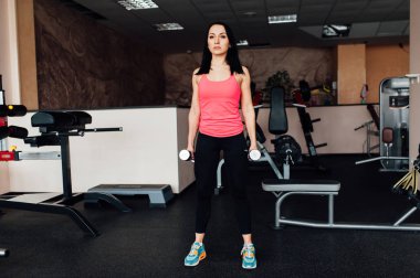 Sportif kız dumbbells ile egzersiz yaparak.