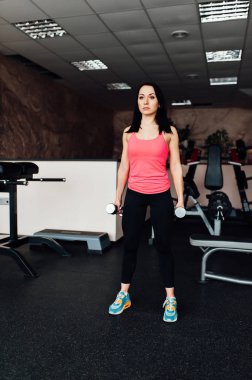 Sportif kız dumbbells ile egzersiz yaparak.