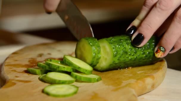 Chica joven está cortando un pepino con un cuchillo — Vídeos de Stock