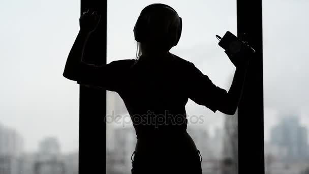 Сексуальная, счастливая женщина слушает музыку и танцует у окна дома . — стоковое видео