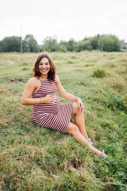 Hamile kadın parkta çim üzerinde oturuyordu