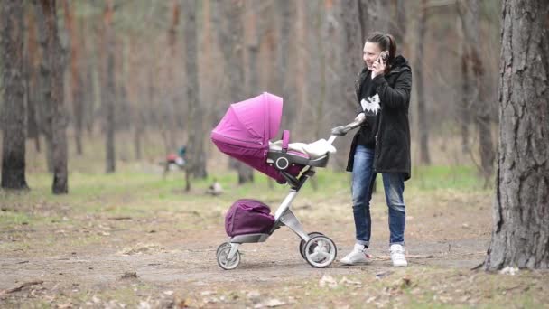 Mamma går med en barnvagn i skogen — Stockvideo