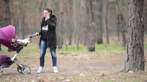 Madre caminando con un cochecito en el bosque — Vídeos de Stock