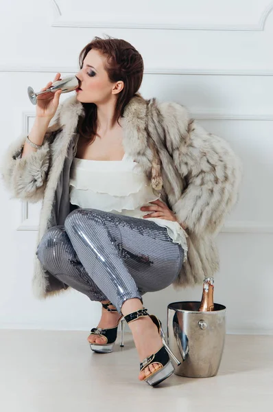 Ragazza sexy sedersi con il vino in pelliccia la sera — Foto Stock