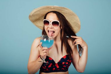 Güneş gözlüklü şehvetli kadın kokteyl içiyor.