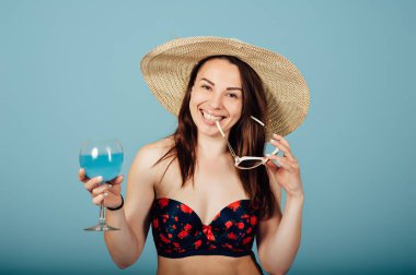 Güneş gözlüklü şehvetli kadın kokteyl içiyor.