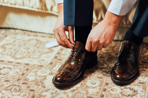 Nahaufnahme junger Mann bindet elegante Schuhe im Haus — Stockfoto