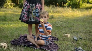 Genç perde üzerinde oturur ve bir elma yiyor