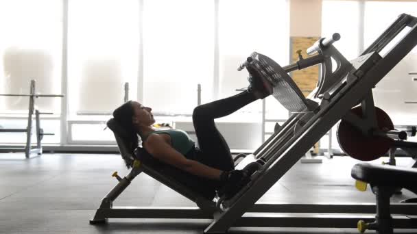 Bonito ajuste menina fazendo exercícios no simulador — Vídeo de Stock